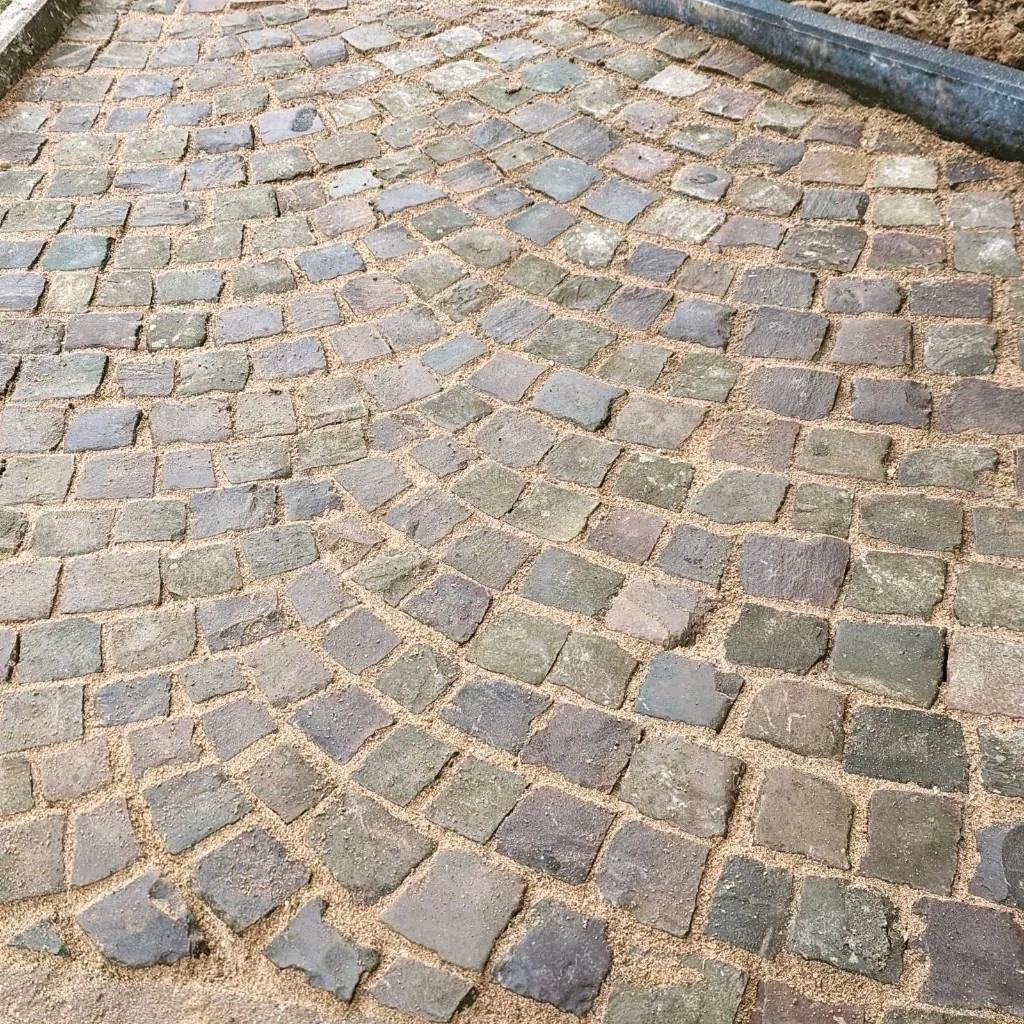 Detailaufnahme eines bogenförmig verlegten Naturstein-Kopfsteinpflasters