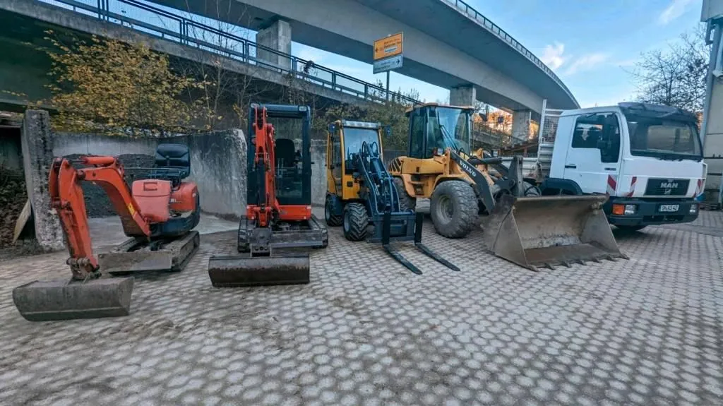 Minibagger, Radlader und Transporter des Betriebs auf einer Stellfläche