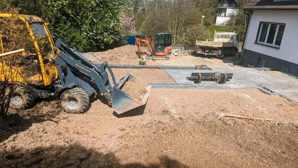 Baustelle einer Einfahrt mit Radlader, Bagger und vorbereitetem Unterbau