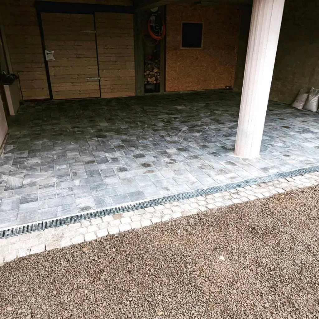 Fertige Pflasterfläche unter einem Carport mit Kiesstreifen als Randabschluss